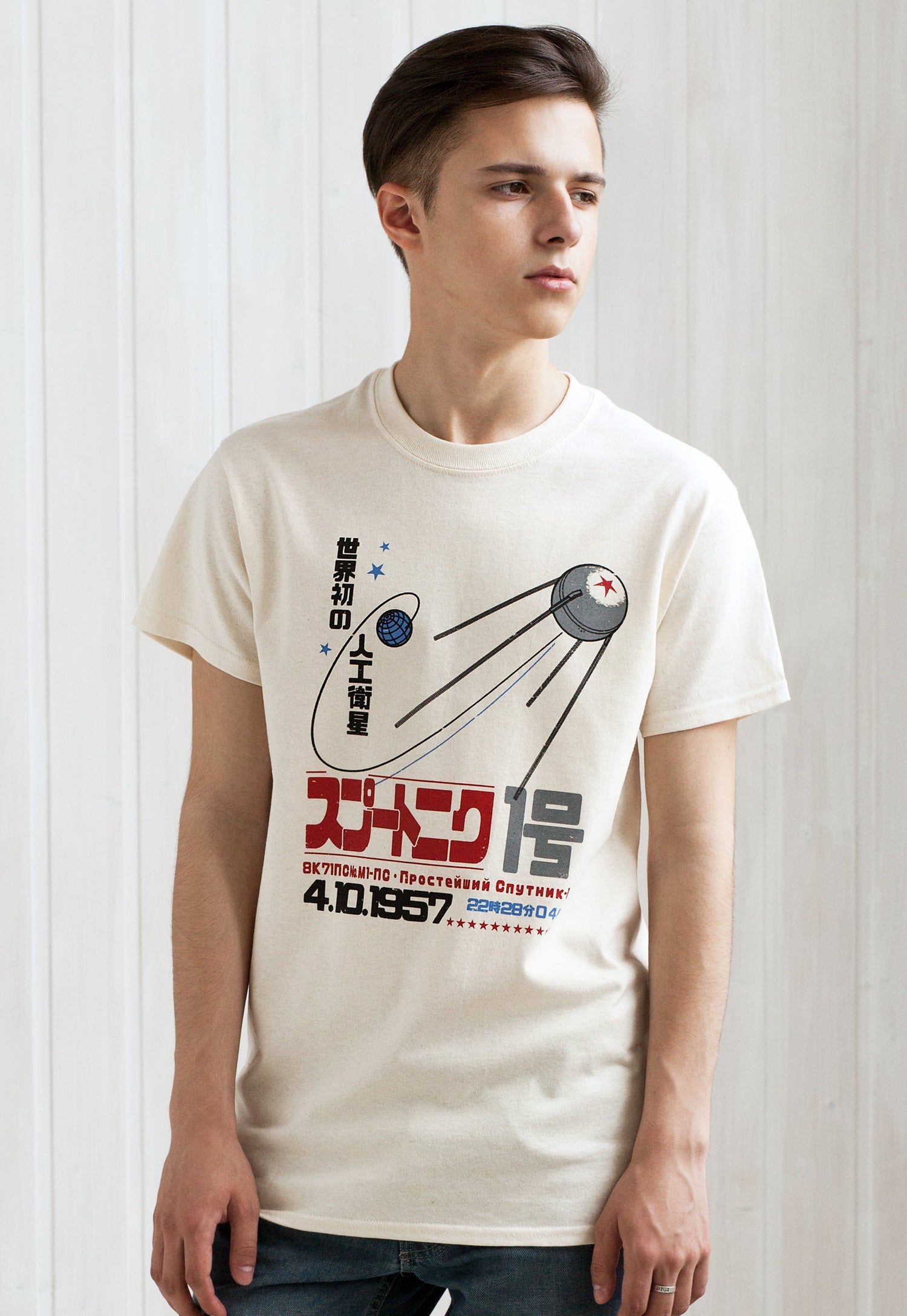 A young man wearing a T Shirt featuring a retro Japanese print of Sputnik 1