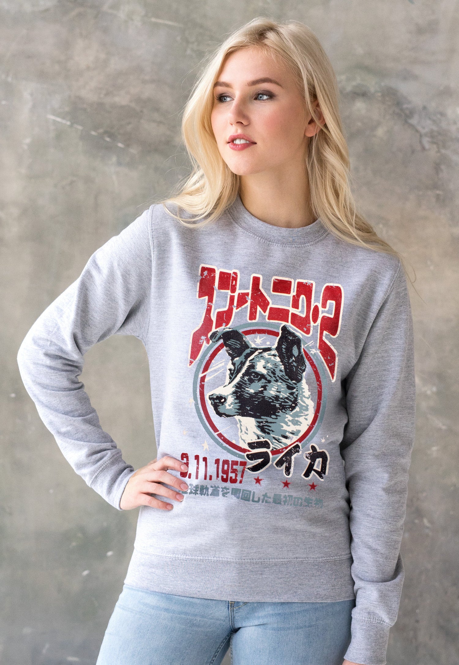 A young blonde woman wearing a cotton grey Sweatshirt with a Japanese retro print of Laika The Space Dog