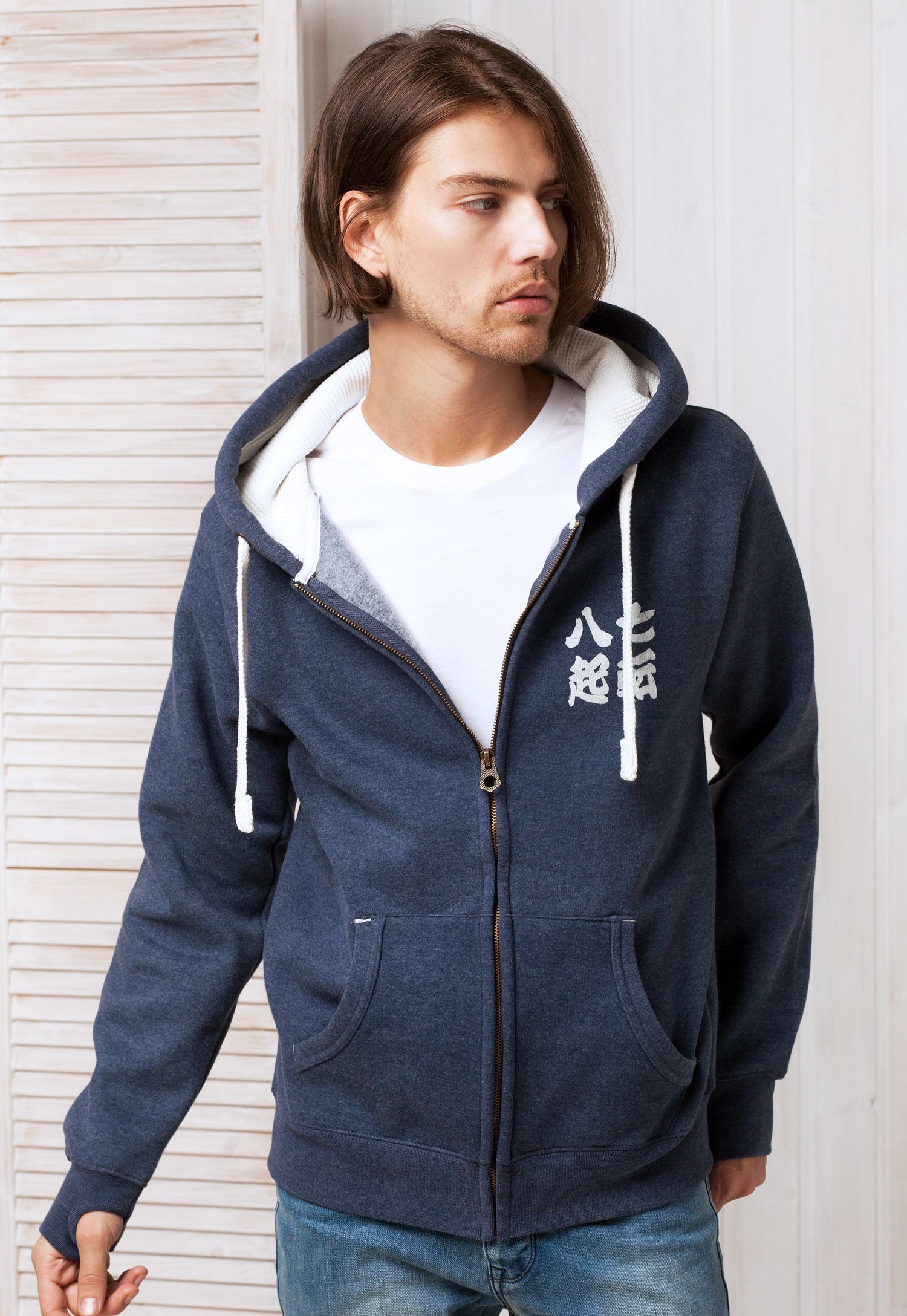 A young man wearing a navy blue Hooded Top with a Japanese calligraphy of expression Nanakorobi Yaoki